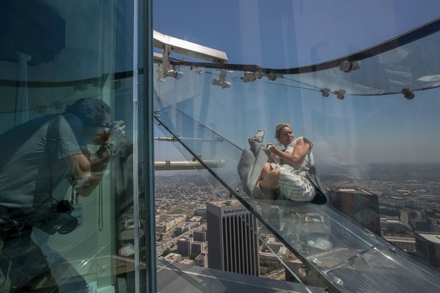 People slide down the Skyslide, a 45-foot (13.7-meter) glass slide 70 floors up on the outside of the US Bank Tower, on June 23, 2016 in Los Angeles, California, during a preview the opening of the attraction. / AFP / DAVID MCNEW (Photo credit should read DAVID MCNEW/AFP/Getty Images)