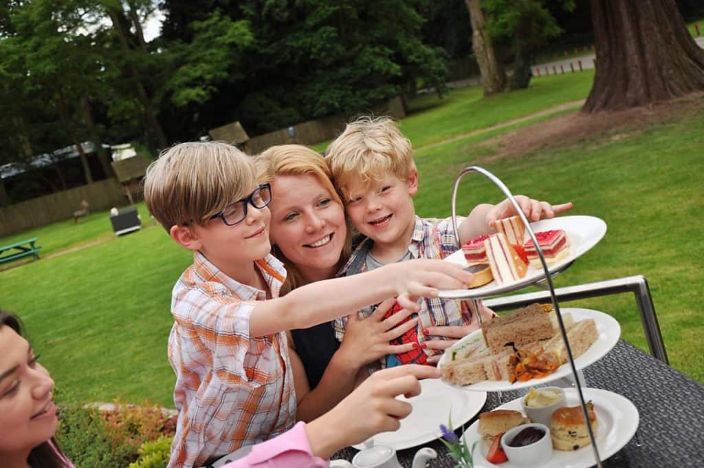 Happy family with kids enjoying a 3-tiered bread and sandwich picnic at the garden of Drayton Manor Hotel 