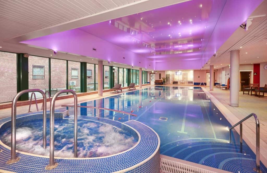 Pink-lighted swimming pool with jacuzzi at family friendly Hilton Bracknell