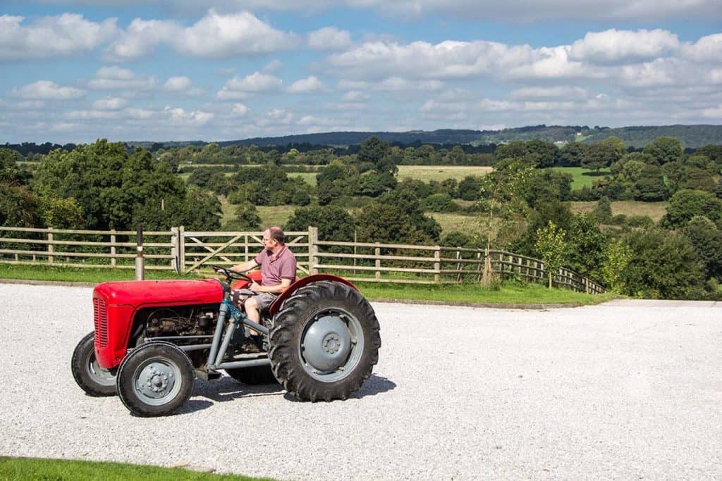 Man riding red tractor at self-catering accommodation, Lower Micklin Farm