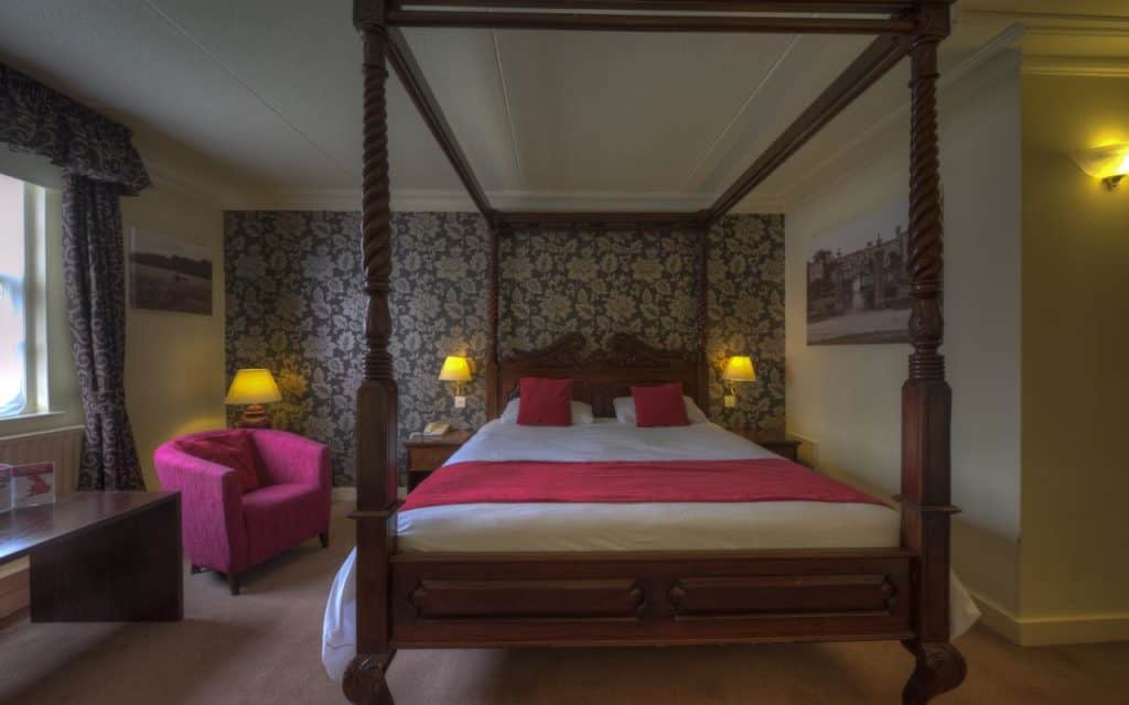 Inside a family room with an elegant four poster bed at Two Brewers Hotel by Greene King Inns