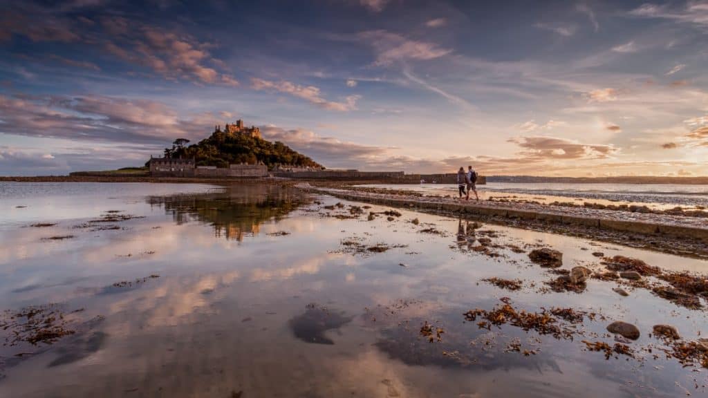 Couple walking across ancient pathways to St Michaels Mount in Cornwall